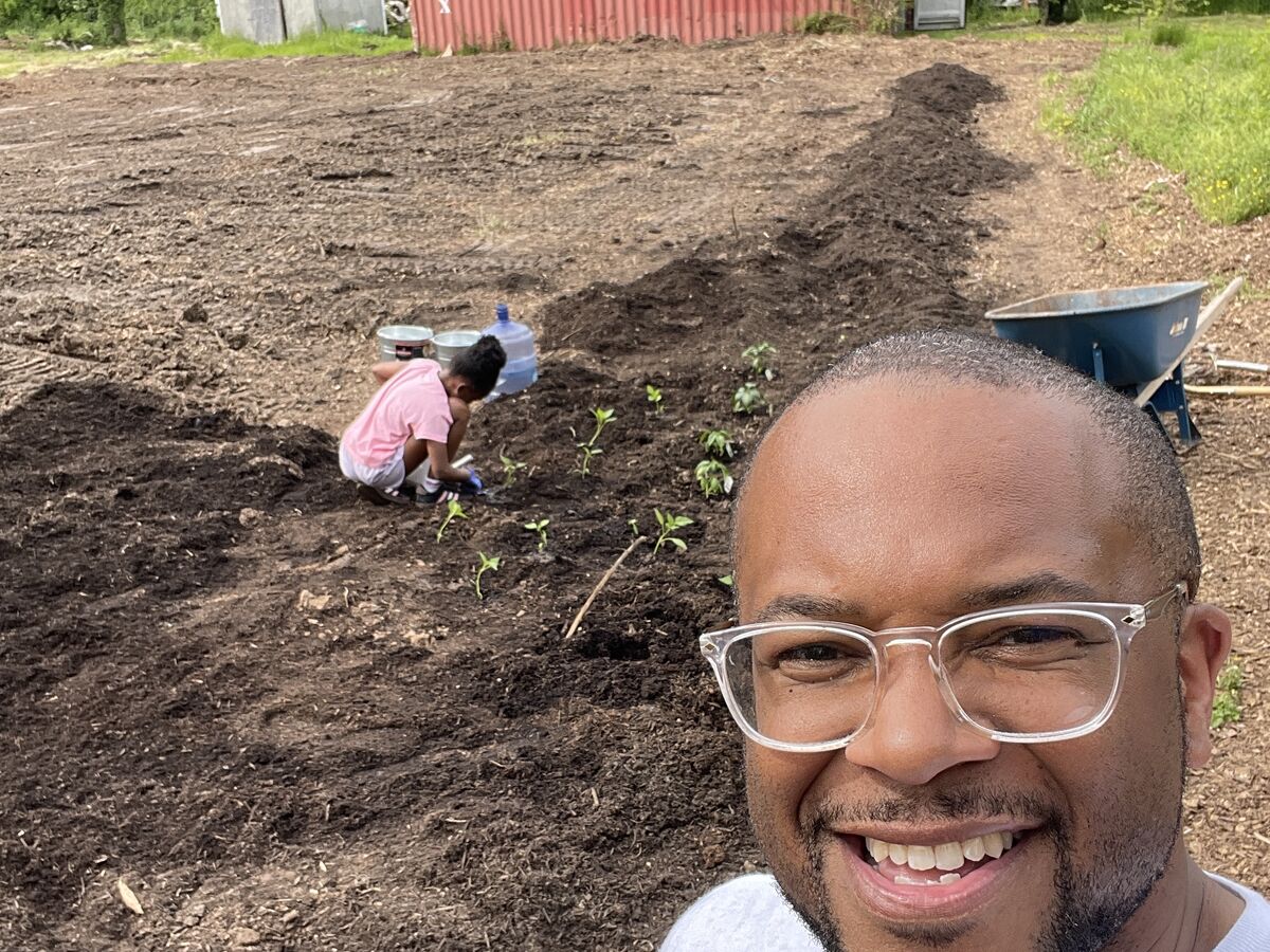 Frank Whitfield at the farm during spring planting, with a young helper setting seedlings in a fresh row